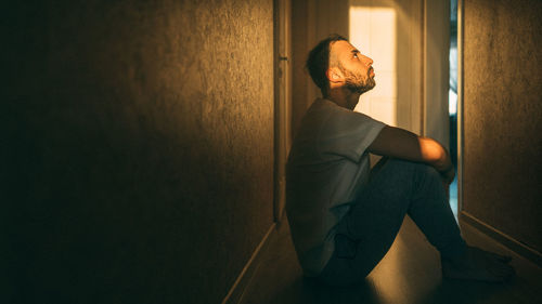 Side view of young man leaning against wall