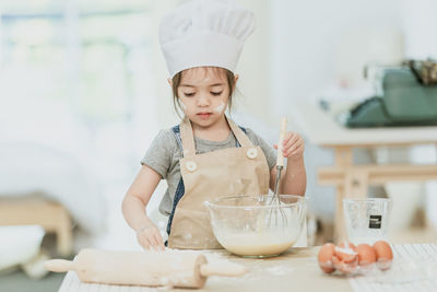 Girl holding ice cream in bowl on table at home