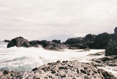 Scenic view of rocks in sea against sky