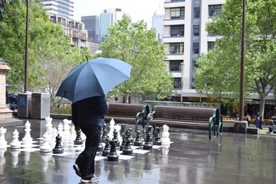 Rear view of man holding umbrella in rain