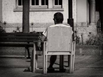 Rear view of man sitting on bench in city