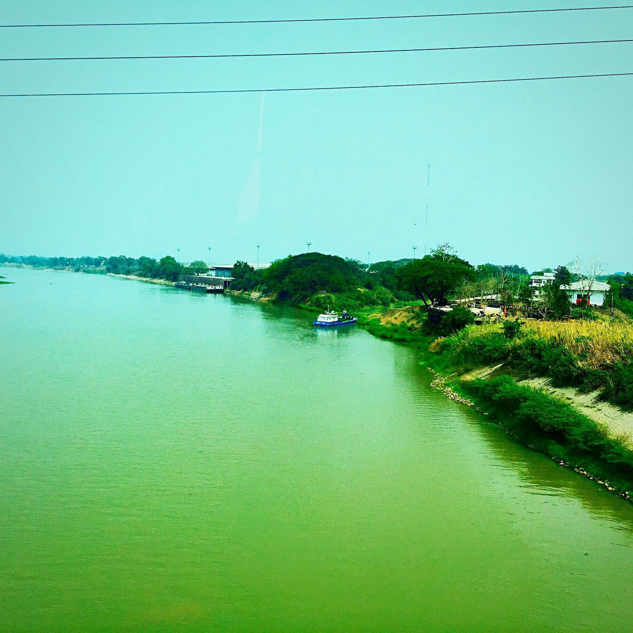 water, clear sky, building exterior, built structure, architecture, sea, copy space, waterfront, blue, tranquil scene, nature, tranquility, scenics, house, beauty in nature, day, beach, outdoors, green color, river