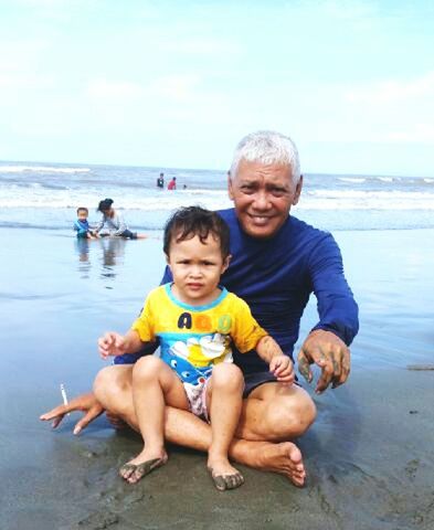 looking at camera, portrait, senior adult, males, full length, bonding, boys, child, baby, men, family, son, beach, sitting, togetherness, adult, happiness, sea, father, senior men, childhood, leisure activity, people, vacations, outdoors, smiling, summer, water, day, cheerful, sky