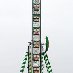 Low angle view of ferris wheel against building against clear sky