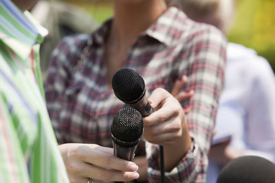 Midsection of female journalist interviewing man on street