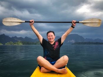 Portrait of smiling man kayaking in lake against sky