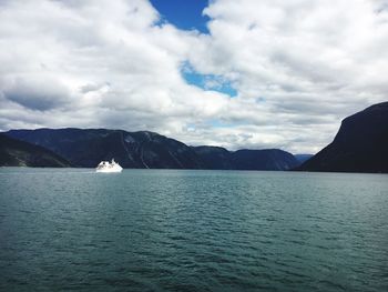 Scenic view of sea by mountains against sky