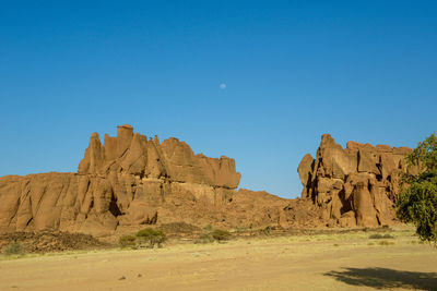 Rock formations on landscape against clear blue sky