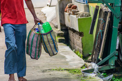 Low section of man with bags walking on street