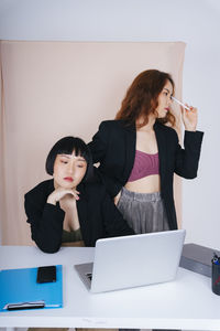 Young woman using phone while sitting on table