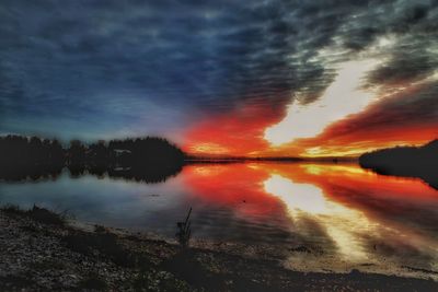 Scenic view of lake against dramatic sky during sunset