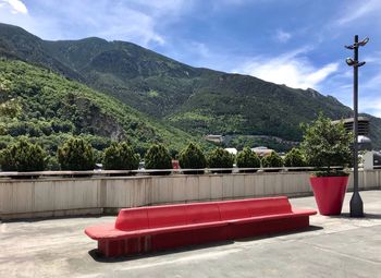 Red deck chairs by trees against mountains