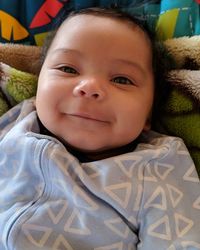 Portrait of cute baby girl lying on bed