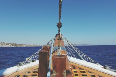 Close-up of ship sailing in sea against clear blue sky