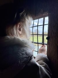 Close-up of child looking through window