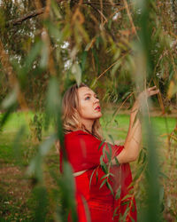 Young woman standing by plants on land