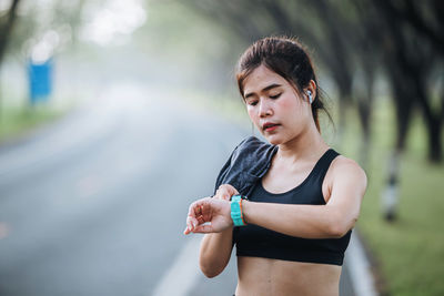 Side view of young woman looking smart watch