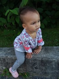 High angle view of cute baby girl sitting on retaining wall