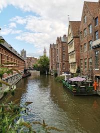 Canal amidst buildings in city against sky