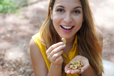 Beautiful healthy girl eating cashew nuts in the park. looks st camera.