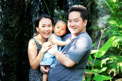 Portrait of happy parents with daughter standing in park