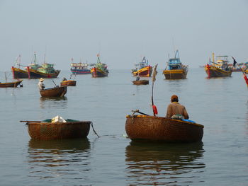 Rear view of man in boat moored on sea against clear sky