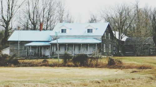 Houses by bare trees against sky