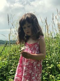 Girl with flowers standing on field