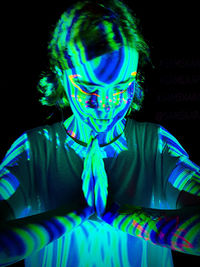 Portrait of woman wearing mask against black background