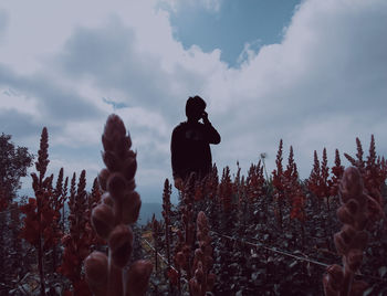 Man standing by tree against sky during winter