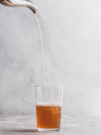 Close-up of moroccan mint tea being poured in glass on grey table