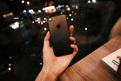 Close-up of hand holding mobile phone on table