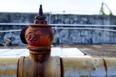 Close-up of rusty metal against retaining wall