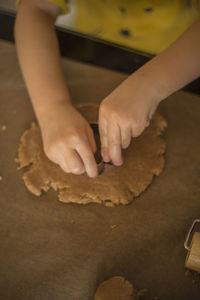 Cropped hands of girl preparing cookie at table