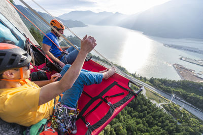 Two men sitting on a portaledge enjoying sunset and view in squamish