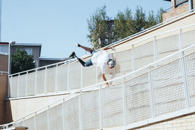 Young man with leg prosthesis performing parkour in the city