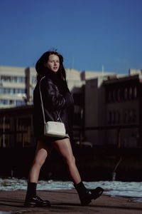 Portrait of young woman standing against building