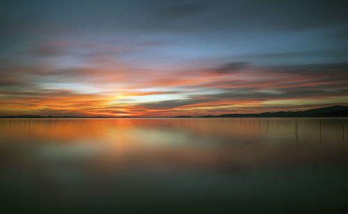 Scenic view of sea against dramatic sky during sunset