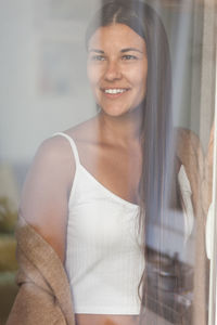 Smiling woman looking away seen through glass window