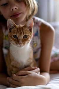 Portrait of cat with girl on bed at home