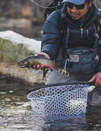 A man catches a brook trout on a cold maine morning