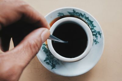 Close-up of hand holding coffee cup on table