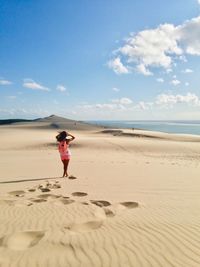 Full length of woman standing on beach against sky