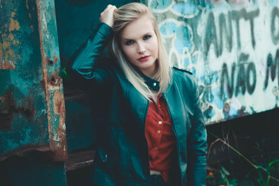 Portrait of confident young woman with hand in hair standing outdoors