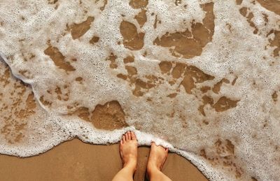 Low section of woman on sand at beach