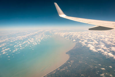 Airplane wing seen through window against sky