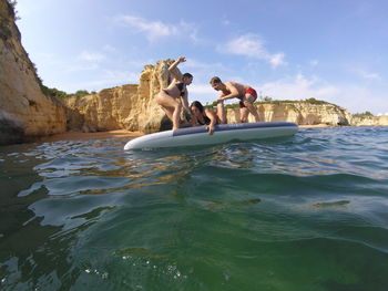 People enjoying at sea shore against sky