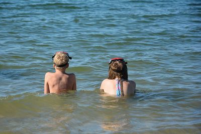 Rear view of two people swimming in sea