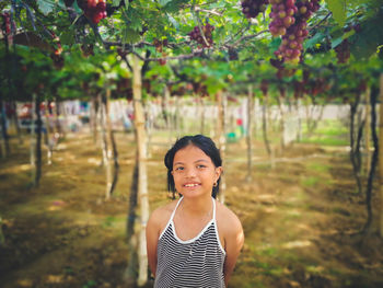 Portrait of smiling young woman standing against trees