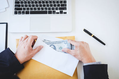 Cropped image of businessman putting currency in envelope